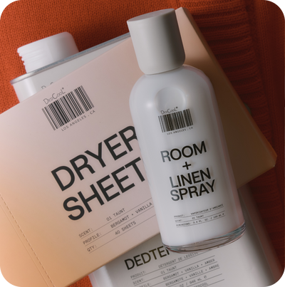 Room and linen spray bottle with dryer sheets on a textured surface
