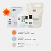 A set of laundry care products arranged on a light gray background: a large cream detergent bag, a white canister, a white box, a white dryer sheet packet, a small white bottle, and a clear bottle with a black cap. An orange burst says it includes a new laundry bag.